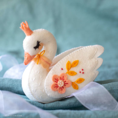 felt swan stuffie on turquoise sheet with pale blue ribbon